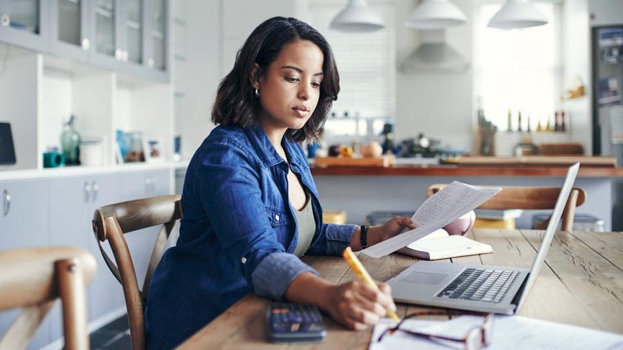 a woman in blazer writing on notebook